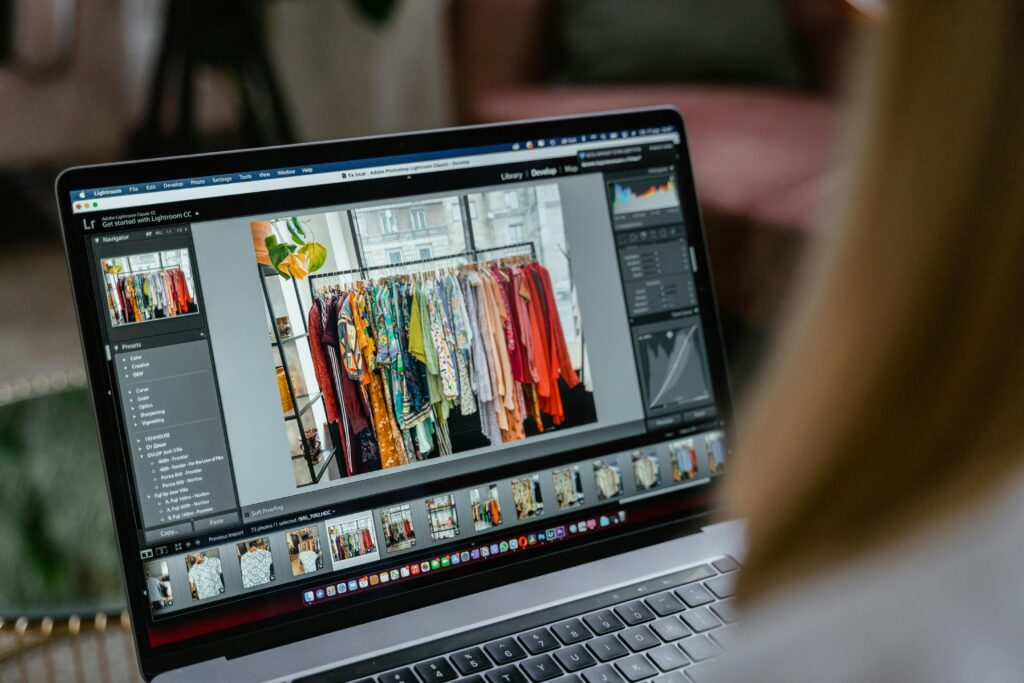 Close-up of a laptop displaying photo editing software with clothes rack in view.